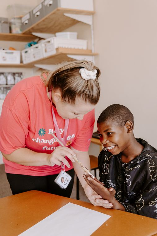 A teacher painting a child's hand