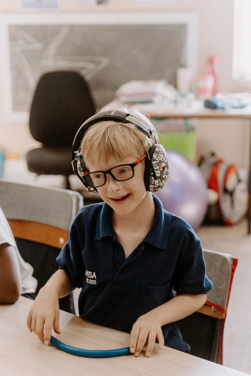 A boy in ear defenders at his desk