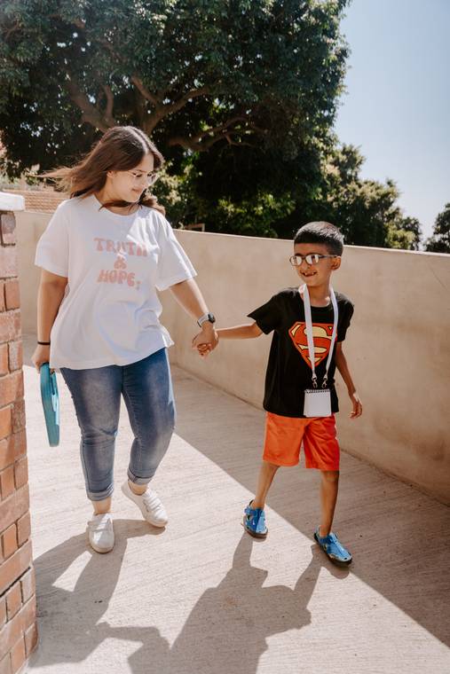 A teacher and child walking to class hand in hand